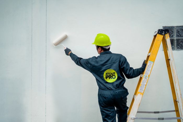 Peintre en train d'appliquer de la peinture blanche de la marque Atout Pro