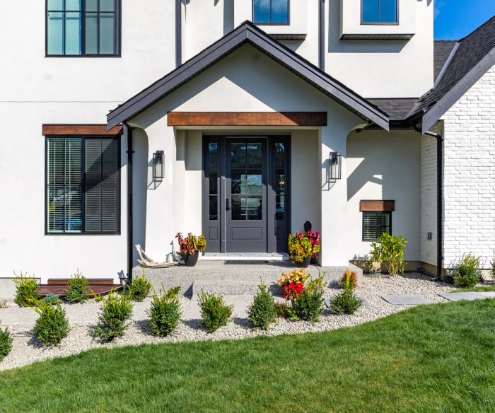 Front view of luxury two garage home with luscious green grass  on a blue sky day.
