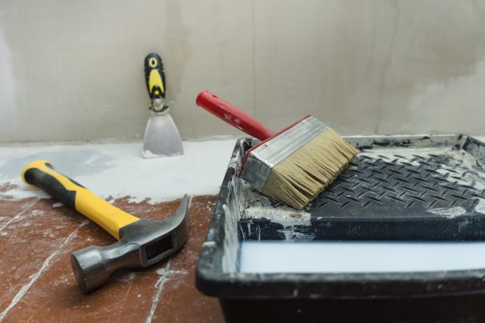 Construction and painting tools lie on the floor during the repair and restoration of the house.Work as a Builder or handyman in the house.Finishing or repairing a room.Job of repairing the apartment