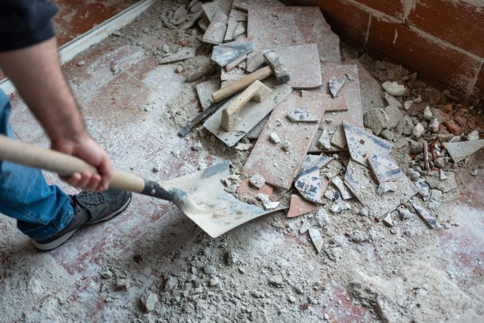 Worker picking up masonry debris with shovel after demolition